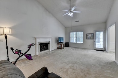 Living area featuring baseboards, light colored carpet, ceiling fan, high vaulted ceiling, and a premium fireplace