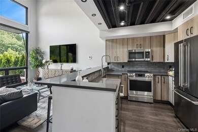 Kitchen featuring stainless steel appliances, a kitchen breakfast bar, a peninsula, tasteful backsplash, and dark wood-style flooring