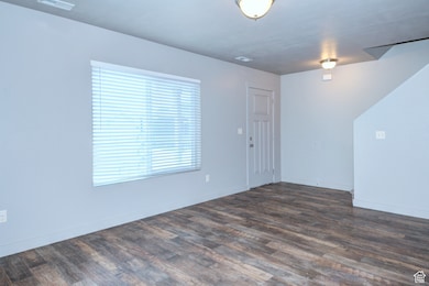 Empty room with dark wood-style floors and baseboards