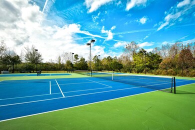 View of tennis court with community basketball court and view of wooded area