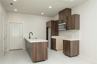 Kitchen with a sink, stainless steel microwave, light marble finish flooring, modern cabinets, and recessed lighting