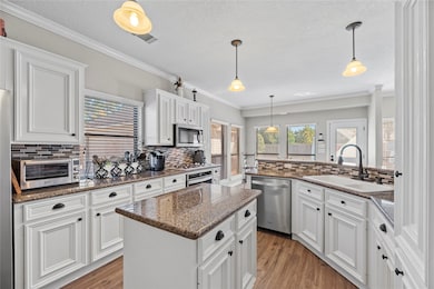 Gorgeous island kitchen features granite countertops, glass tile backsplash and white cabinetry.