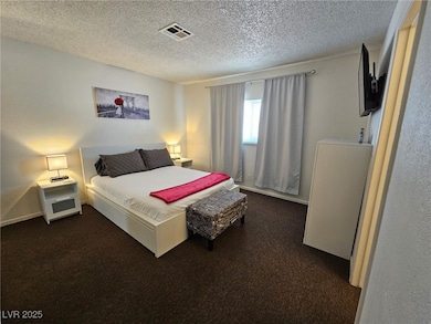 Bedroom featuring dark colored carpet and a textured ceiling
