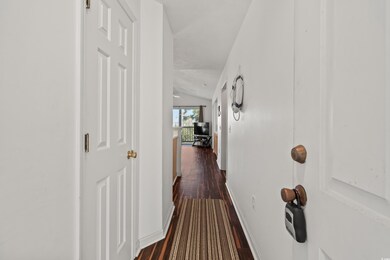 Corridor with vaulted ceiling and dark hardwood / 