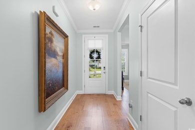 Doorway to outside with ornamental molding and wood finished floors
