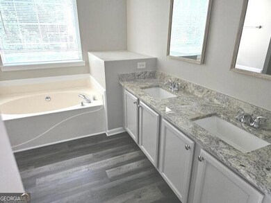 Full bathroom with newly  installed floors, double vanity, and a bath