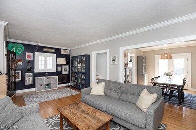 Living room featuring ornamental molding, light wood-type flooring, and a textured ceiling