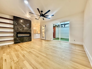 Unfurnished living room featuring a premium fireplace, light wood-style flooring, and a ceiling fan