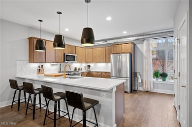 Kitchen with light countertops, a peninsula, tasteful backsplash, appliances with stainless steel finishes, and a breakfast bar