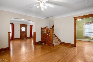 Entrance foyer with light wood-style flooring, stairway, ceiling fan, and arched walkways