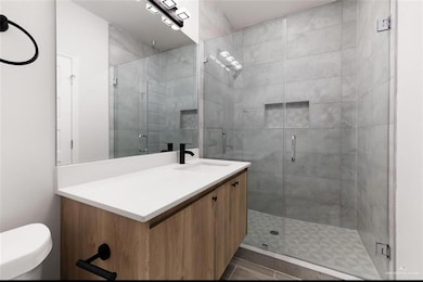 Full bathroom with vanity, a stall shower, and dark tile patterned flooring