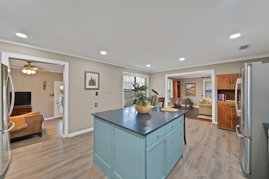 Kitchen featuring blue cabinetry, freestanding refrigerator, light wood-type flooring, recessed lighting, and a center island