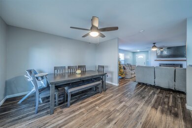 Dining room featuring dark wood-type flooring, a fireplace, and a ceiling fan