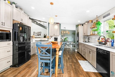 Kitchen with black appliances, a sink, decorative backsplash, light countertops, and open shelves