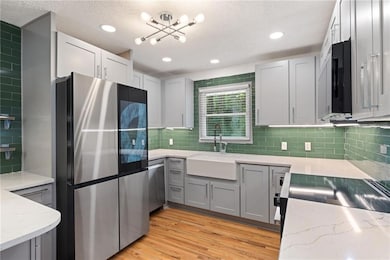 Kitchen featuring light stone counters, a sink, ap