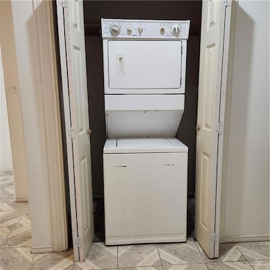 Washroom featuring stacked washer / drying machine and baseboards
