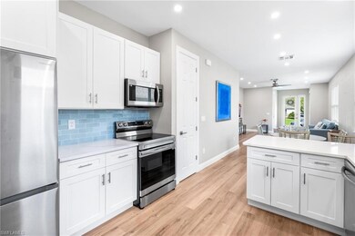 Kitchen featuring stainless steel appliances, white cabinetry, open floor plan, recessed lighting, and light wood finished floors