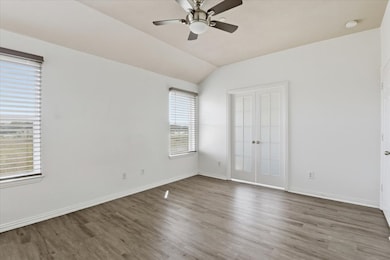 Unfurnished bedroom featuring wood finished floors, lofted ceiling, a ceiling fan, and a closet