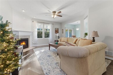 Living room featuring wood finished floors, a tile fireplace, and a ceiling fan
