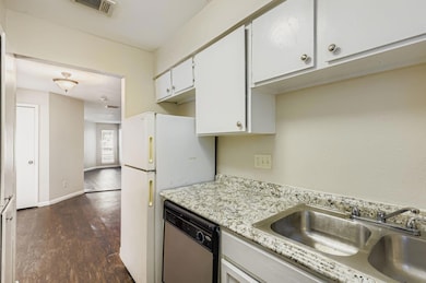 Kitchen with dark wood-style flooring, white cabinetry, and stainless steel dishwasher