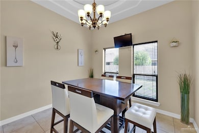 Dining room featuring a chandelier, light tile patterned floors, baseboards, and a raised ceiling