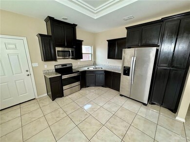 Kitchen featuring light tile patterned floors, light stone counters, a sink, visible vents, and appliances with stainless steel finishes