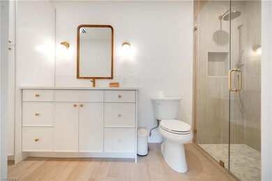 Full bath featuring toilet, a stall shower, wood f