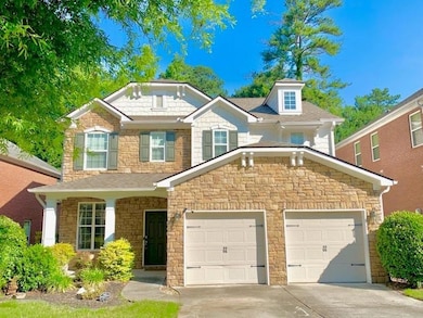 View of front of property featuring stone siding, driveway, and a garage