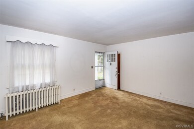 Spare room featuring light carpet and radiator heating unit