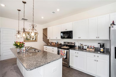 Kitchen with stainless steel appliances, a sink, white cabinetry, and recessed lighting