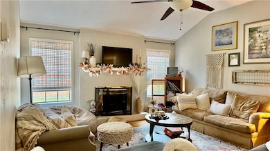Living room featuring a fireplace, wood finished floors, lofted ceiling, and a ceiling fan
