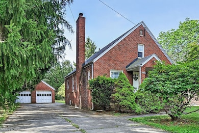 View of property exterior with a chimney, brick siding, an outbuilding, and a detached garage