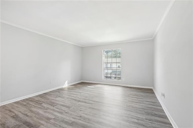 Unfurnished room featuring crown molding, wood finished floors, and baseboards