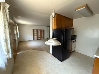 Kitchen with freestanding refrigerator, white electric stove, brown cabinets, and open floor plan
