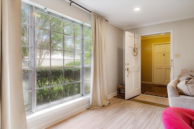 Living room with crown molding, recessed lighting, light wood-style flooring, and baseboards