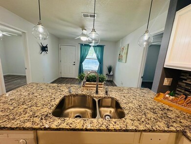 Kitchen with a ceiling fan, light stone counters,
