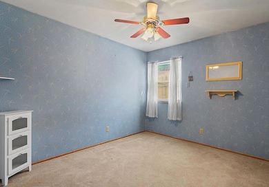 Carpeted empty room with a ceiling fan and baseboa
