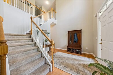 Foyer entrance featuring a high ceiling, stairs, and wood finished floors