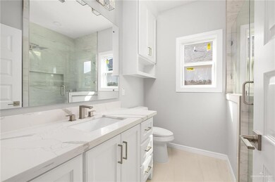 Full bathroom featuring toilet, a marble finish shower, baseboards, and vanity