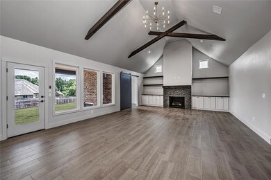 Unfurnished living room with a barn door, beam ceiling, a chandelier, high vaulted ceiling, and wood finished floors