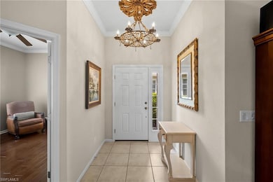 Tiled foyer entrance with crown molding, a chandelier, and a ceiling fan