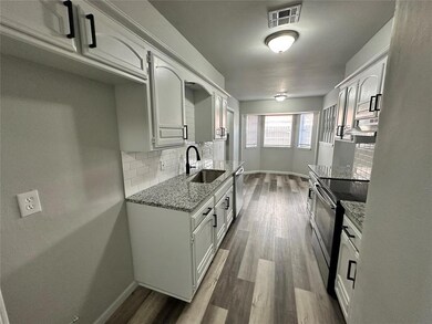 Kitchen with a sink, appliances with stainless steel finishes, baseboards, and stone countertops