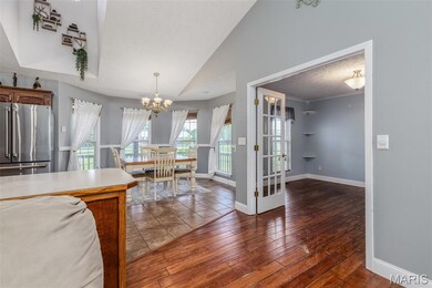 Dining room featuring a chandelier, baseboards, vaulted ceiling, wood finished floors, and a textured ceiling