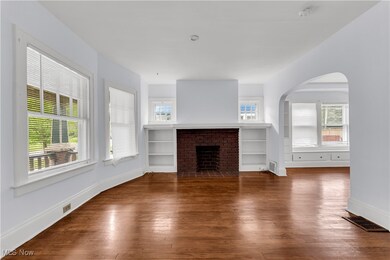 Unfurnished living room featuring built in features, a brick fireplace, a healthy amount of sunlight, and hardwood / wood-style floors