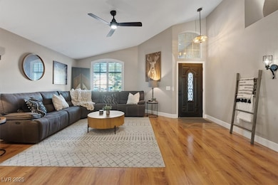Living room with ceiling fan, light wood-style flooring, and high vaulted ceiling