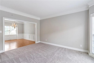 Unfurnished room with crown molding, a chandelier, and light carpet