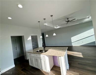 Kitchen featuring a sink, an island with sink, whi