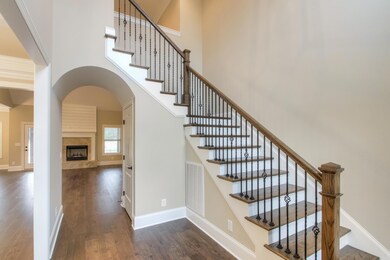 Grand foyer with beautiful stair case and an arched door way that leads to the great room.