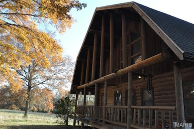 View of side of home with log exterior and a shingled roof