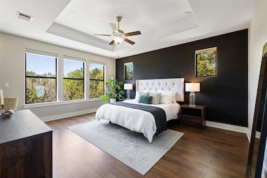Bedroom featuring a raised ceiling, dark wood fin